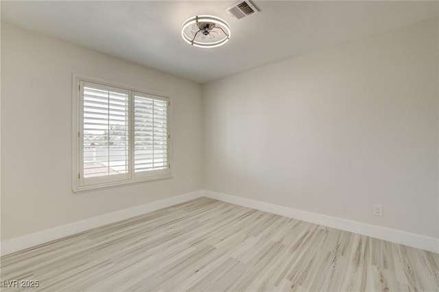 empty room with visible vents, baseboards, and wood finished floors