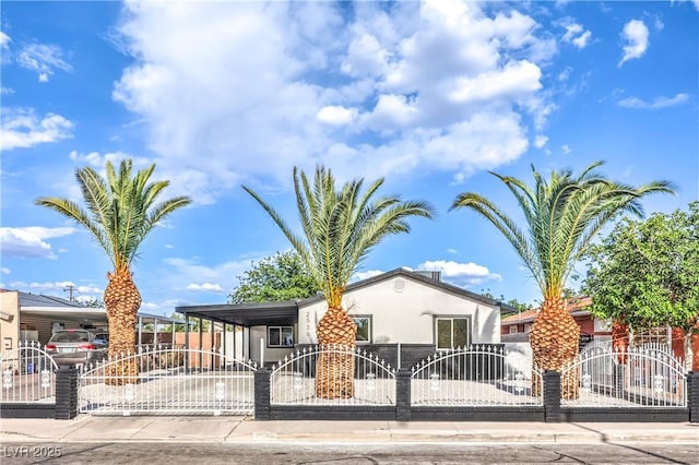 view of front of property featuring driveway, a fenced front yard, a gate, and stucco siding