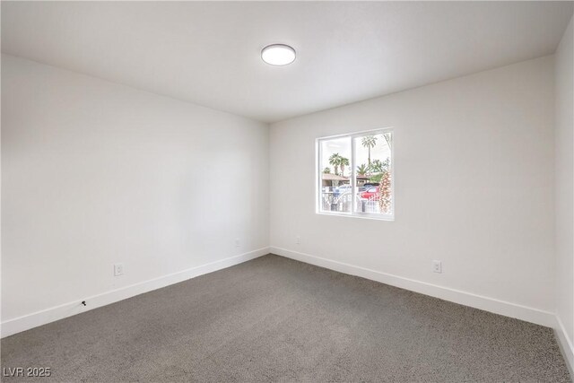 unfurnished room with baseboards and dark colored carpet