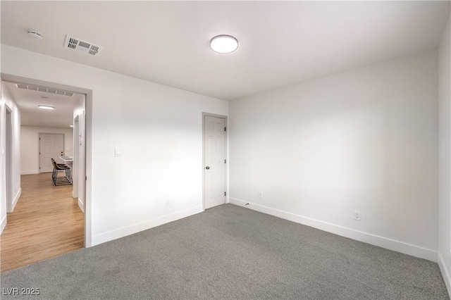 carpeted empty room featuring baseboards and visible vents