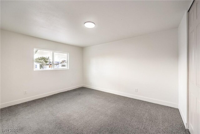 spare room with baseboards and dark carpet