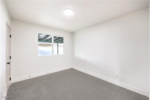 unfurnished room featuring baseboards and dark colored carpet