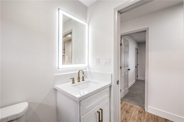 bathroom with vanity, baseboards, toilet, and wood finished floors