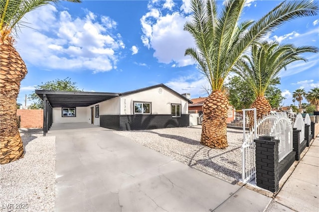 ranch-style house featuring fence, stucco siding, an attached carport, a gate, and concrete driveway