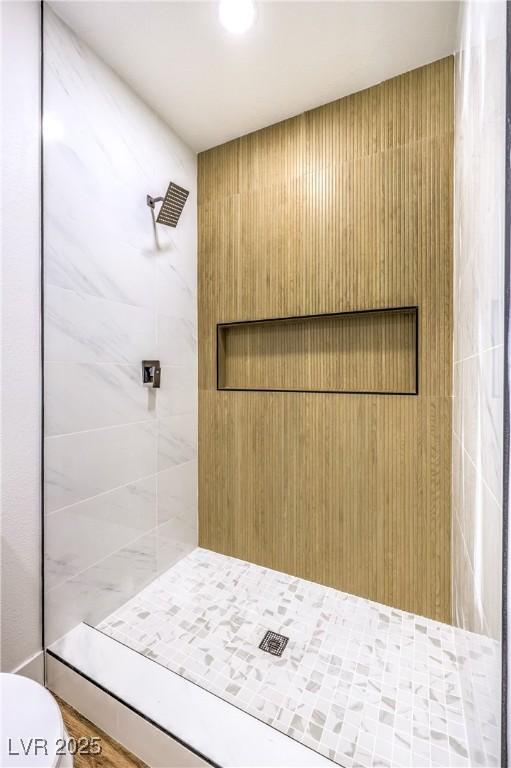 bathroom featuring toilet and a tile shower
