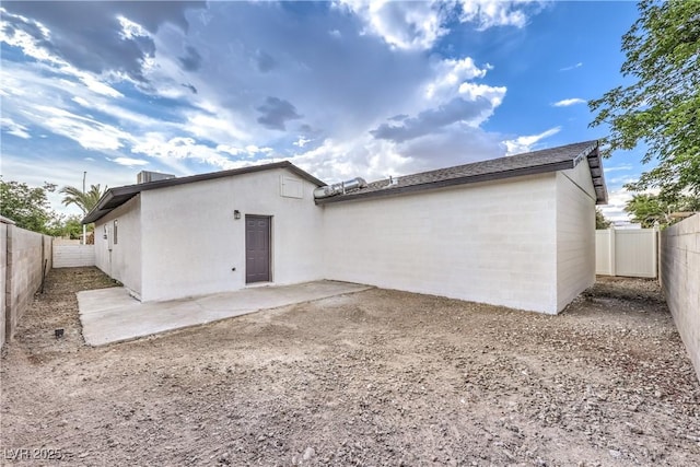 rear view of property with a fenced backyard and a patio