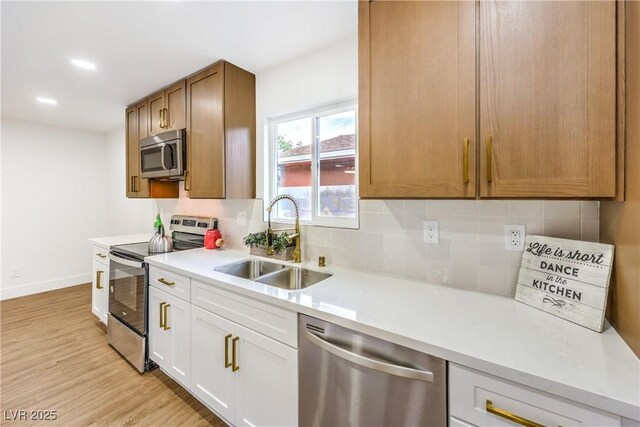kitchen featuring light wood-type flooring, light countertops, tasteful backsplash, a sink, and stainless steel appliances