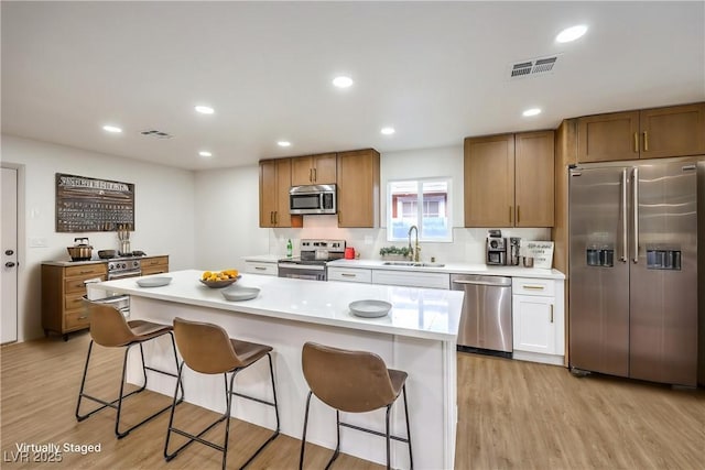 kitchen featuring stainless steel appliances, visible vents, a breakfast bar, and a sink