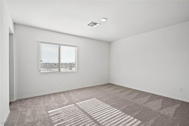 empty room with baseboards, visible vents, and carpet
