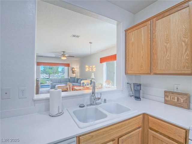 kitchen with a sink, light countertops, a ceiling fan, hanging light fixtures, and open floor plan