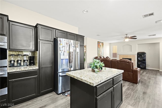kitchen featuring light wood finished floors, a ceiling fan, stainless steel refrigerator with ice dispenser, and visible vents