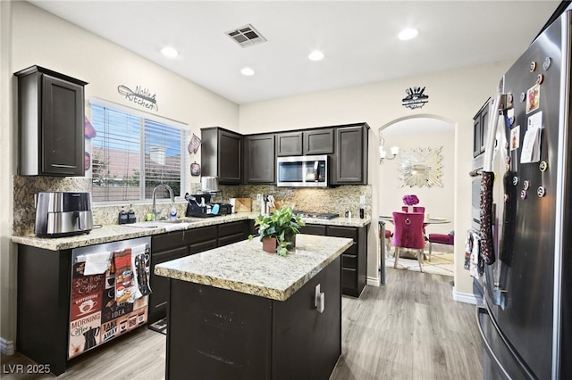 kitchen featuring visible vents, decorative backsplash, a sink, light wood finished floors, and appliances with stainless steel finishes