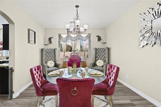dining space featuring baseboards, arched walkways, wood finished floors, and a notable chandelier
