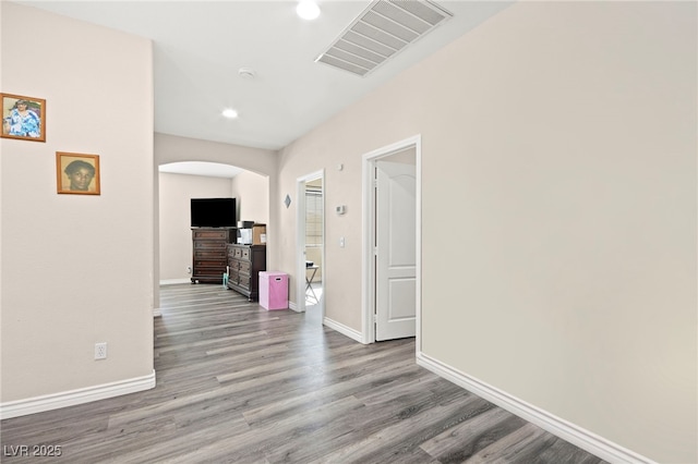 corridor featuring arched walkways, recessed lighting, baseboards, wood finished floors, and visible vents