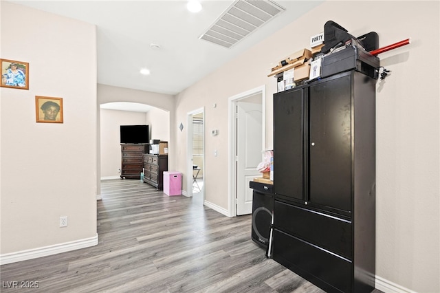 hall featuring visible vents, arched walkways, baseboards, and light wood-type flooring