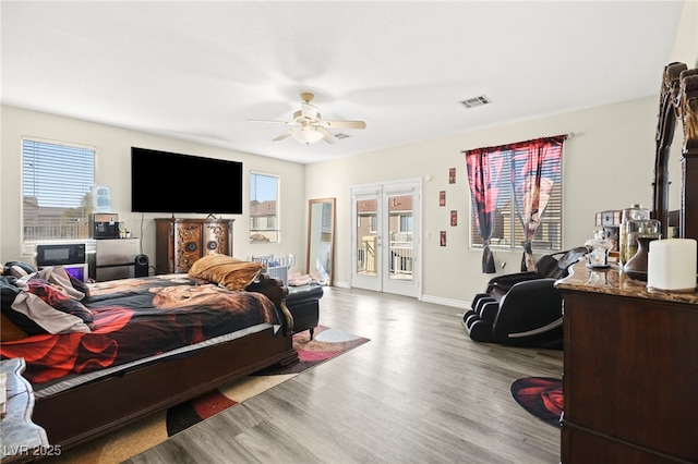 bedroom with ceiling fan, visible vents, wood finished floors, baseboards, and access to outside
