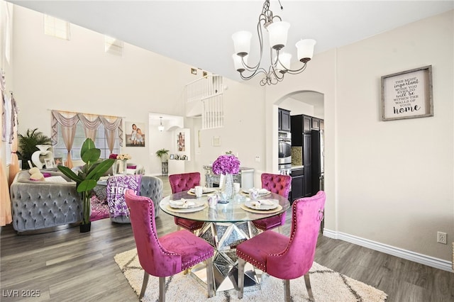 dining area featuring arched walkways, baseboards, wood finished floors, and a chandelier