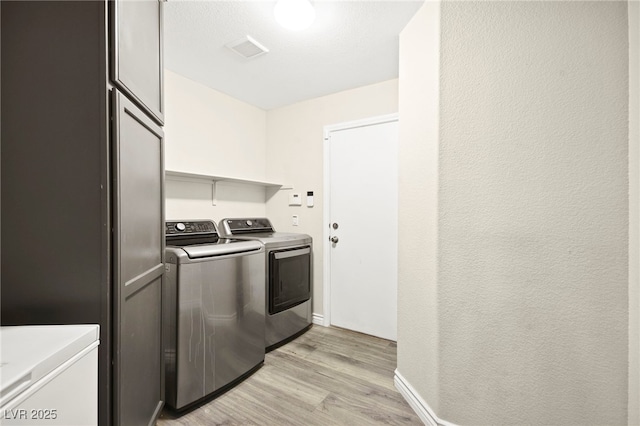 clothes washing area with laundry area, visible vents, washer and dryer, baseboards, and light wood-type flooring