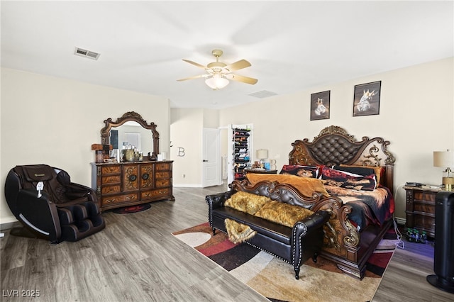 bedroom featuring visible vents, baseboards, ceiling fan, and wood finished floors