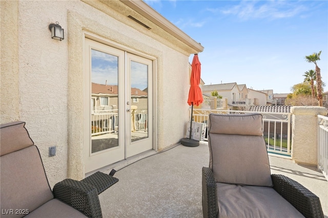 view of patio / terrace with a balcony, french doors, and a residential view