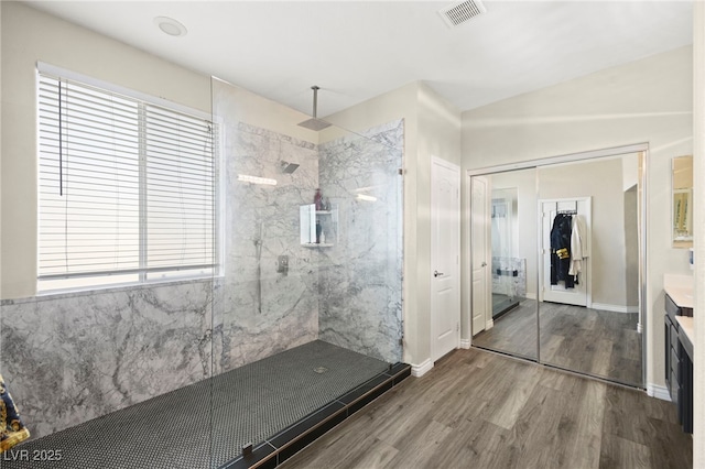 bathroom featuring plenty of natural light, a marble finish shower, wood finished floors, and visible vents