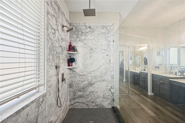 bathroom with a marble finish shower, vanity, and wood finished floors