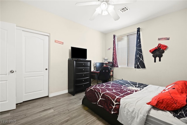 bedroom with a ceiling fan, baseboards, visible vents, and wood finished floors