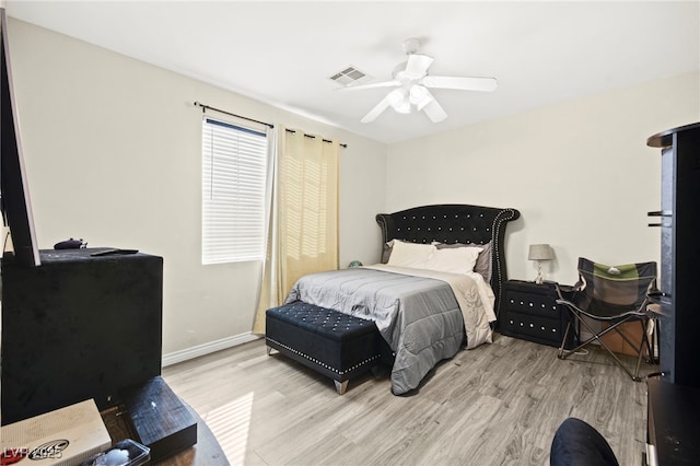 bedroom featuring baseboards, ceiling fan, wood finished floors, and visible vents
