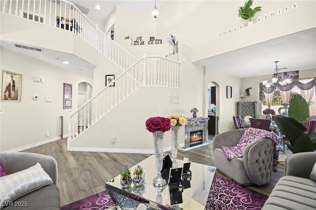 living area with visible vents, arched walkways, stairs, and a notable chandelier