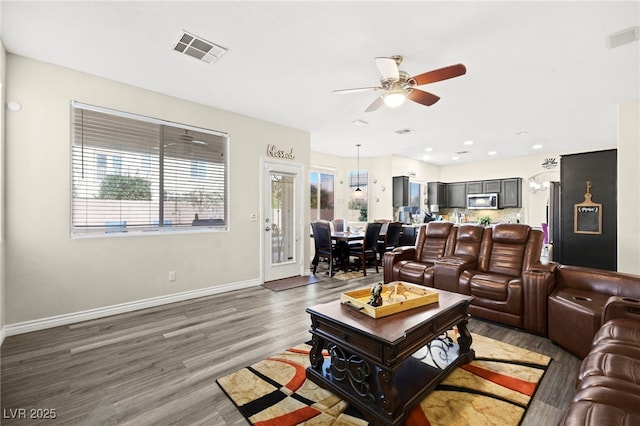 living area with visible vents, light wood-style floors, ceiling fan, and baseboards