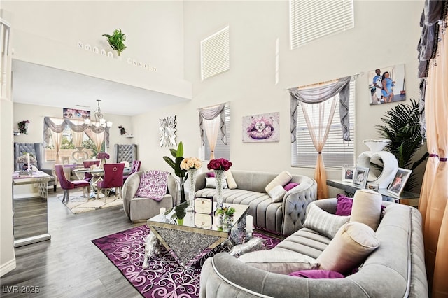 living room with an inviting chandelier, a towering ceiling, wood finished floors, and visible vents