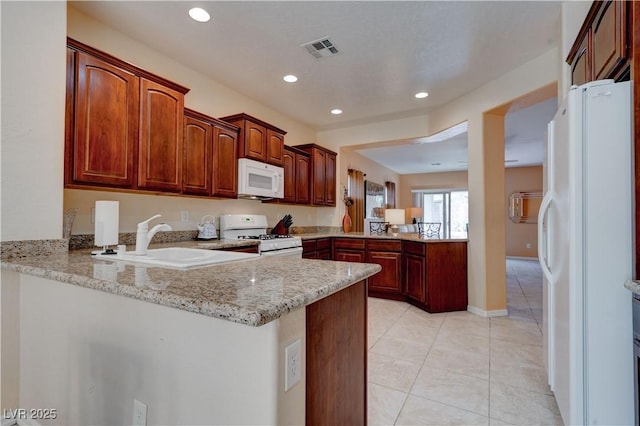 kitchen with visible vents, light tile patterned floors, a sink, a peninsula, and white appliances