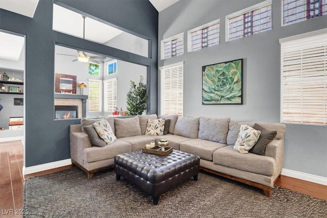 1861 Windward Ct, Henderson, NV 89012 - living area featuring a glass covered fireplace, wood finished floors, a towering ceiling, baseboards, and ceiling fan
