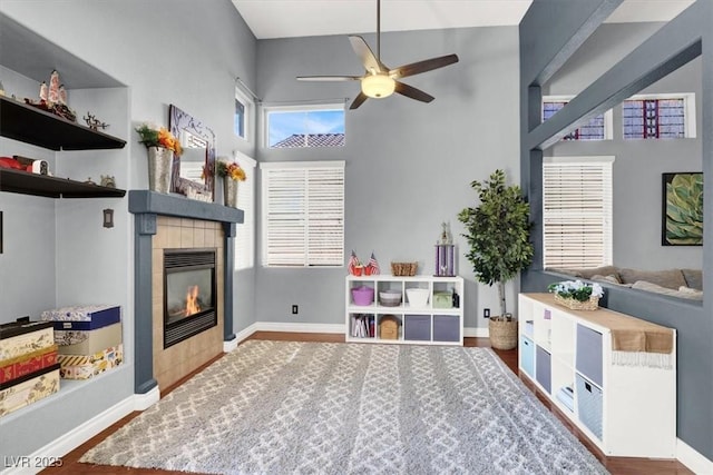 1861 Windward Ct, Henderson, NV 89012 - game room with ceiling fan, a high ceiling, a fireplace, baseboards, and wood finished floors