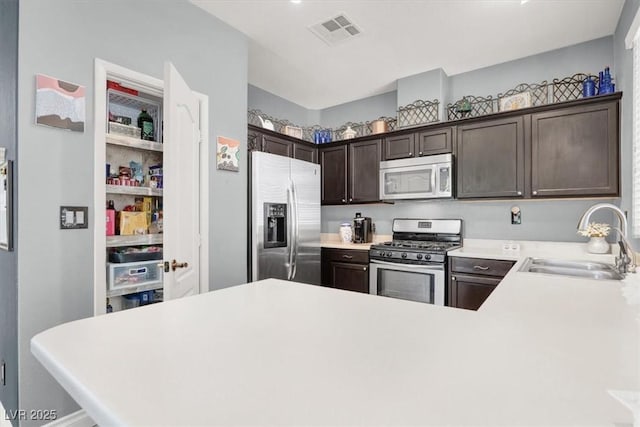 1861 Windward Ct, Henderson, NV 89012 - kitchen with dark brown cabinetry, appliances with stainless steel finishes, a sink, light countertops, and visible vents