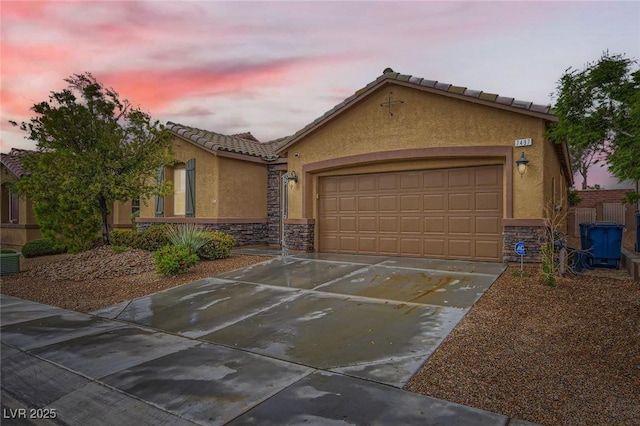 view of front facade featuring stone siding, stucco siding, a garage, and driveway