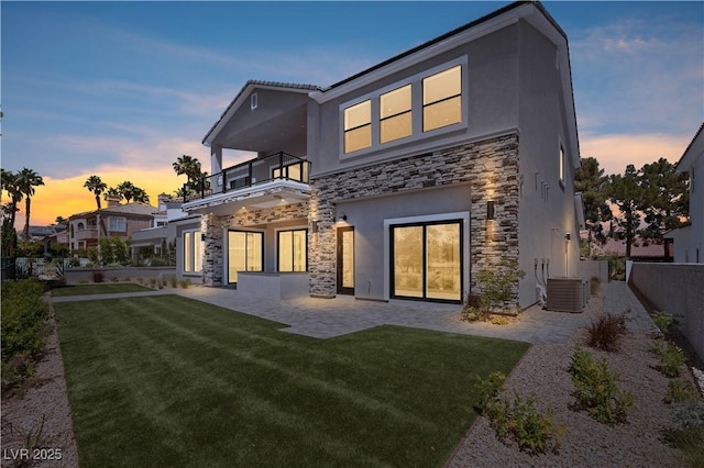 8721 Robinson Ridge Dr, Las Vegas, NV 89117 - back of house at dusk featuring stone siding, a balcony, stucco siding, and a patio area