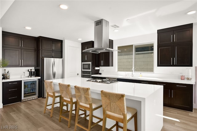 9815 Evergreen Pine St, Las Vegas, NV 89166 - kitchen with visible vents, island range hood, a sink, wine cooler, and stainless steel appliances