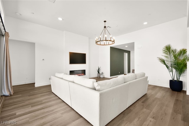 9815 Evergreen Pine St, Las Vegas, NV 89166 - living room with a glass covered fireplace, baseboards, light wood finished floors, and a chandelier