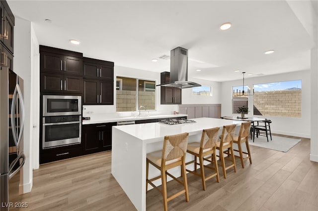 9815 Evergreen Pine St, Las Vegas, NV 89166 - kitchen featuring island exhaust hood, a center island, light wood-type flooring, a breakfast bar, and stainless steel appliances