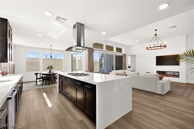 9815 Evergreen Pine St, Las Vegas, NV 89166 - kitchen featuring light wood-style floors, stainless steel appliances, island exhaust hood, and a notable chandelier