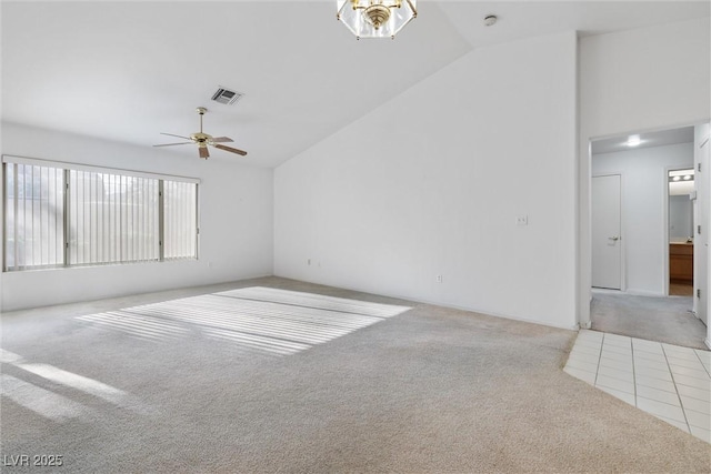 carpeted empty room featuring visible vents, a ceiling fan, and vaulted ceiling