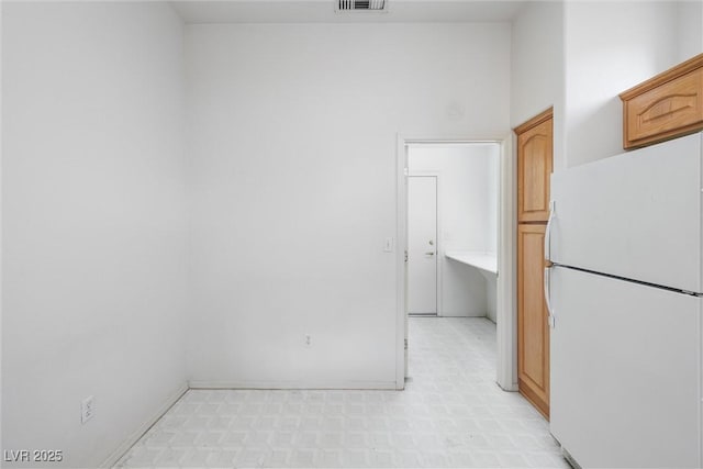 kitchen with freestanding refrigerator, baseboards, visible vents, and light floors
