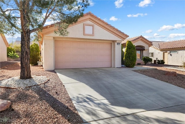 view of front facade with a tiled roof, a garage, driveway, and stucco siding