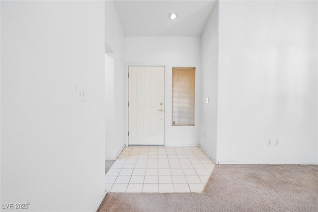 unfurnished room with light colored carpet, baseboards, and light tile patterned flooring