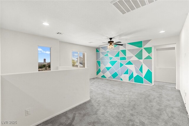 empty room featuring carpet floors, an accent wall, recessed lighting, and visible vents