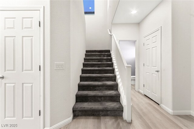 staircase featuring baseboards, recessed lighting, and wood finished floors