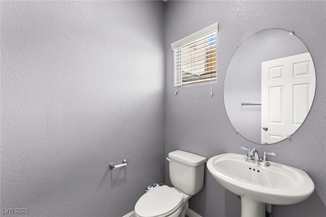 bathroom with baseboards, a sink, and toilet
