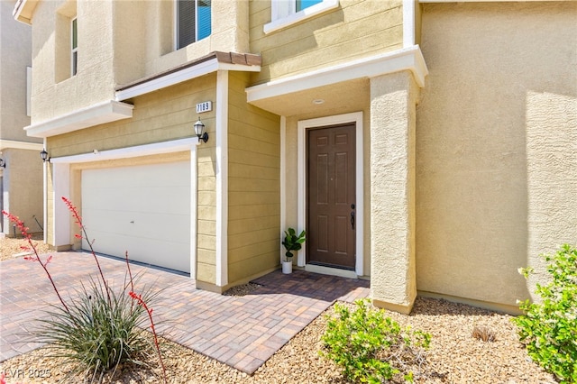 property entrance with a garage and stucco siding