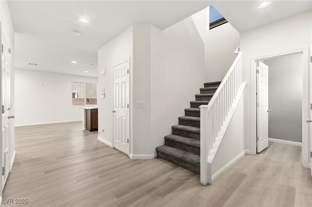 staircase featuring baseboards, recessed lighting, and wood finished floors